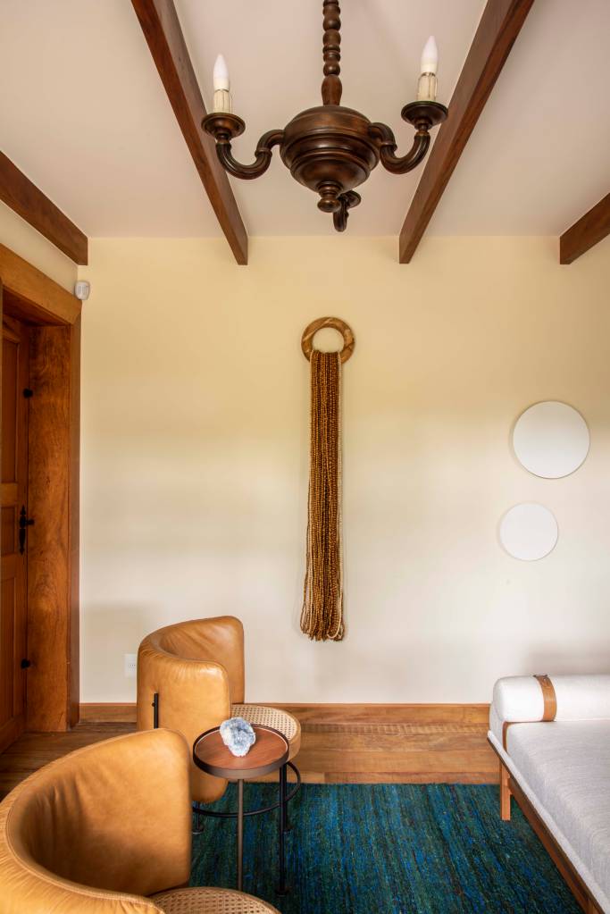 6-retrofit-em-duas-casas-de-familia-recupera-estilo-colonial-das-construcoes Sala com vigas de madeira no teto e poltronas marrons