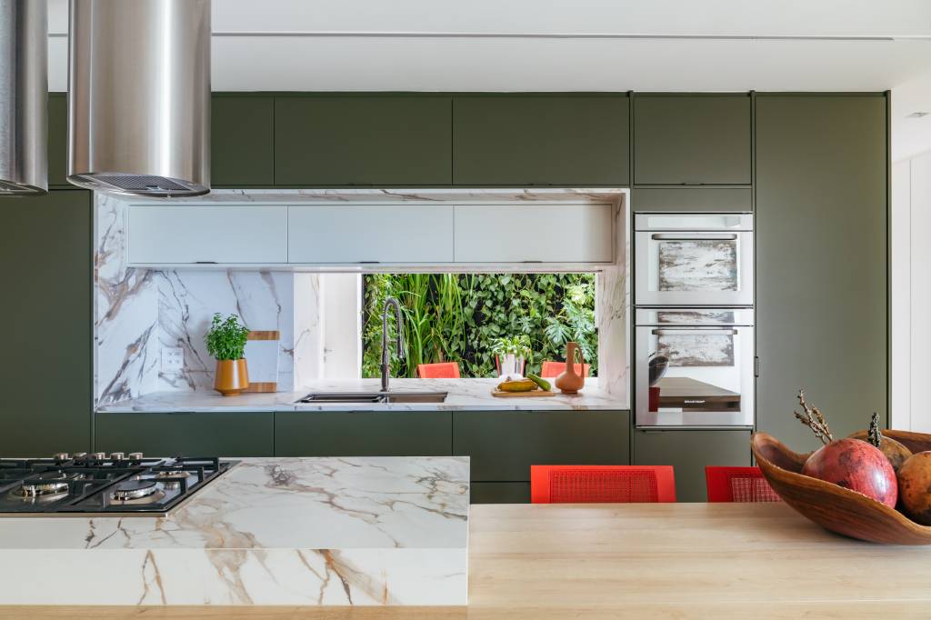 cobertura-sauna-paredes-vidro-e-area-gourmet-balancos-vivian-reimers-13-cozinha-verde Cobertura tem sauna com paredes de vidro e área gourmet com balanços. Projeto de Vivian Reimers. Na foto, cozinha com marcenaria verde musgo, ilha e bancada para refeições, cadeiras laranja.