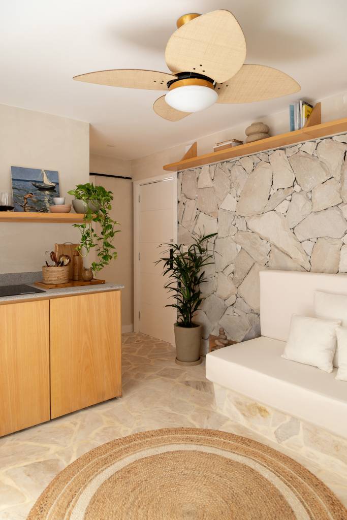 ape-terreo-45-m-cara-casa-de-praia-area-externa-integrada-casa-tauari-02-sala-pedra Apê térreo de 45 m² ganha cara de casa de praia com área externa integrada. Projeto de Casa Tauari. Na foto, sala de estar, parede de pedra, sofá branco, tapete redondo de fibra.
