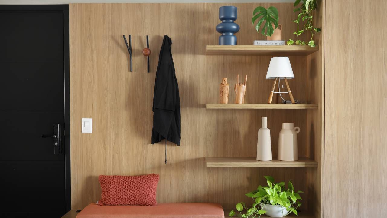 Apê de 68 m² tem espaço para chapelaria e painel com portas mimetizadas. Projeto do Studio 92 Arquitetura. Na foto, móvel com chapelaria e banco