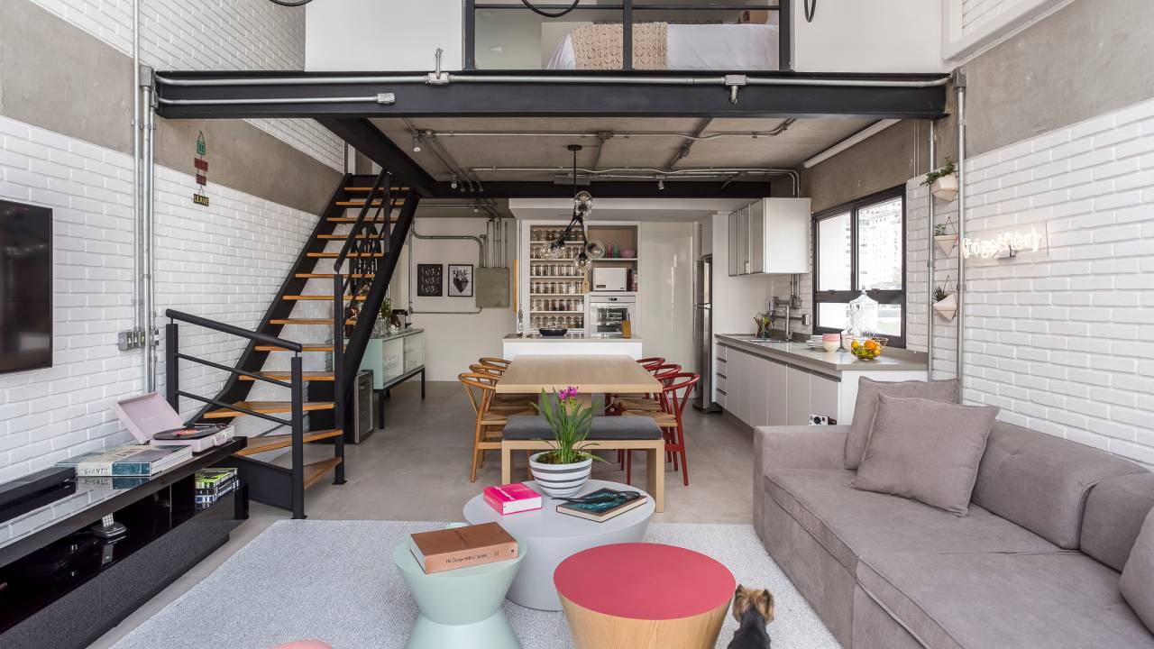 Como escolher e decorar lofts? Projeto de Korman Arquitetos. Na foto, loft com tijolinhos brancos expostos e decorações coloridas