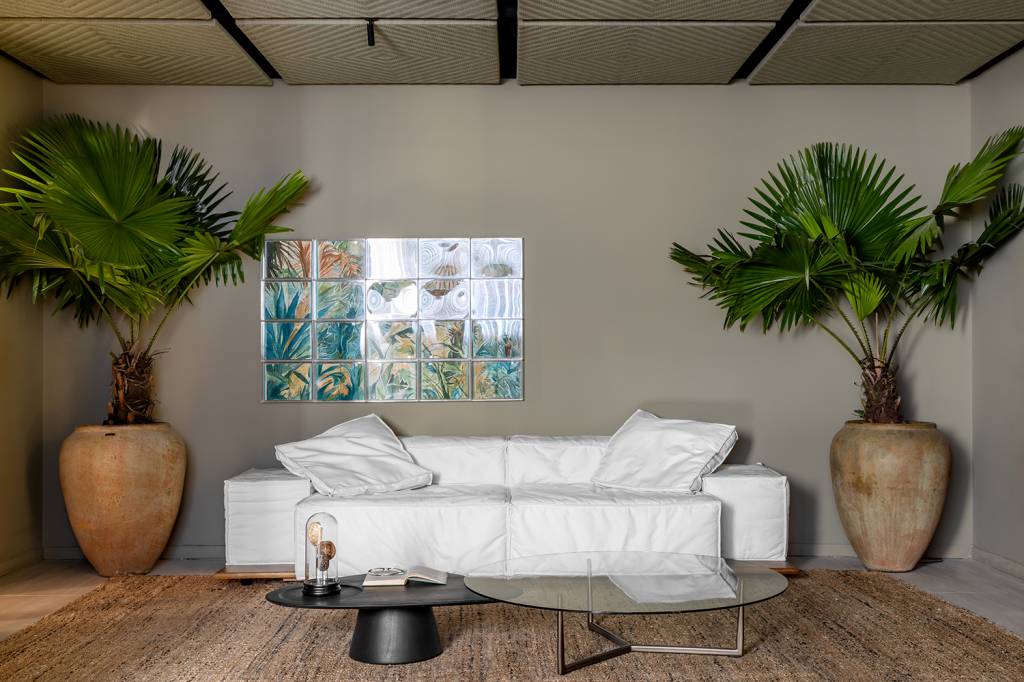 loft-83-m-acolhimento-tem-cama-e-sofas-exclusivos-daniela-schmitt-casacor-sc-2024-05-plantas-palmeira Loft de 83 m² pensado para o acolhimento tem cama e sofás exclusivos. Projeto de Daniela Schmitt para a CASACOR SC 2024. Na foto, sala de estar, sofá branco, palmeiras.