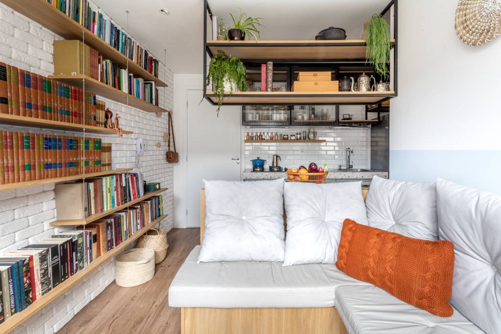 miniape-25-m-sofa-de-canto-alemao-com-bau-estante-mil-livros-lemarchi-arquitetura-13-sala Miniapê de 25 m² tem sofá de canto alemão com baú e estante de mil livros. Projeto de Lemarchi Arquitetura. Na foto, cozinha integrada, prateleira com livros.